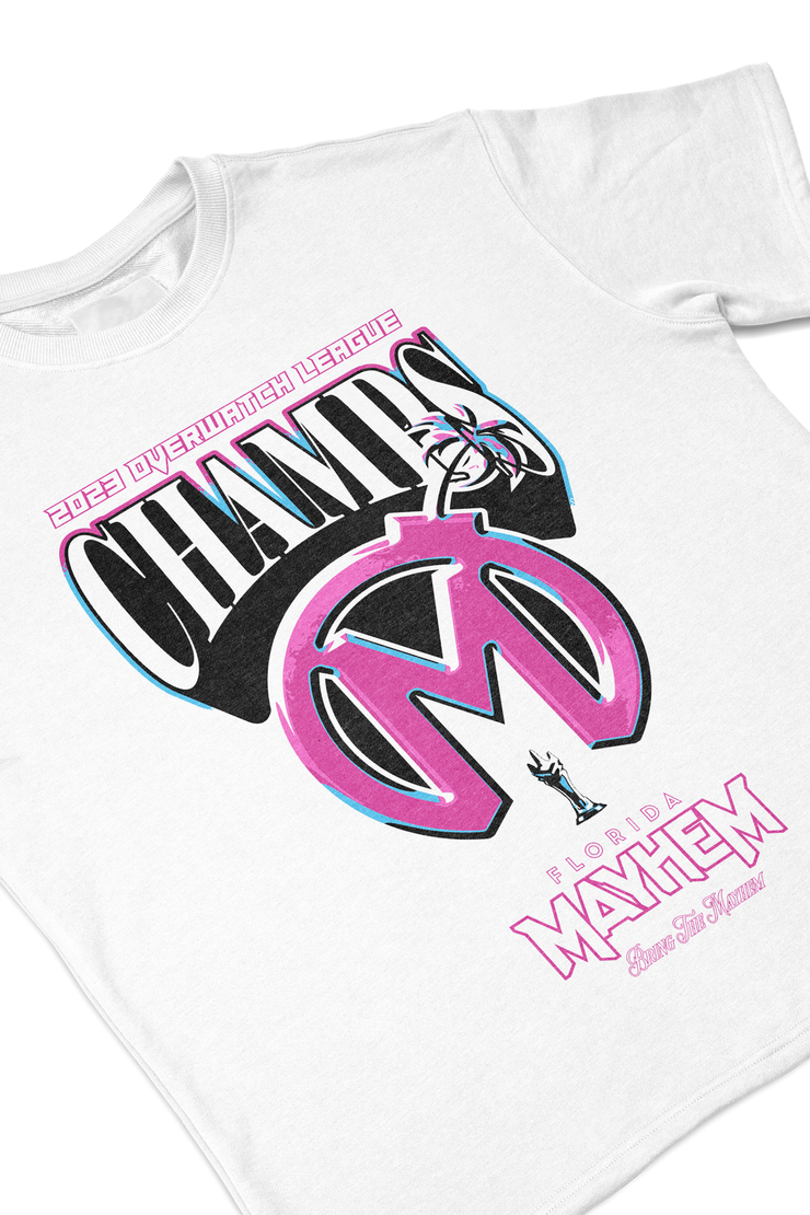 A close-up of a white short-sleeved t-shirt featuring a bold design. The graphic showcases "2023 Overwatch League CHAMPS" in a combination of black, pink, and cyan. Beneath, there&