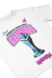 A clos up of white short-sleeved t-shirt featuring vibrant graphics. At the top, the word "Finals" in cyan is paired with "Overwatch League Finals" in pink. Below, the word "CHAMPIONS" is boldly displayed in pink, with a detailed blue and cyan trophy design beneath. The year 2023 flank the trophy, emphasizing the championship year. The phrase "Florida Mayhem" is written in bright pink at the bottom, with the team's small pink bomb logo placed near the collar.